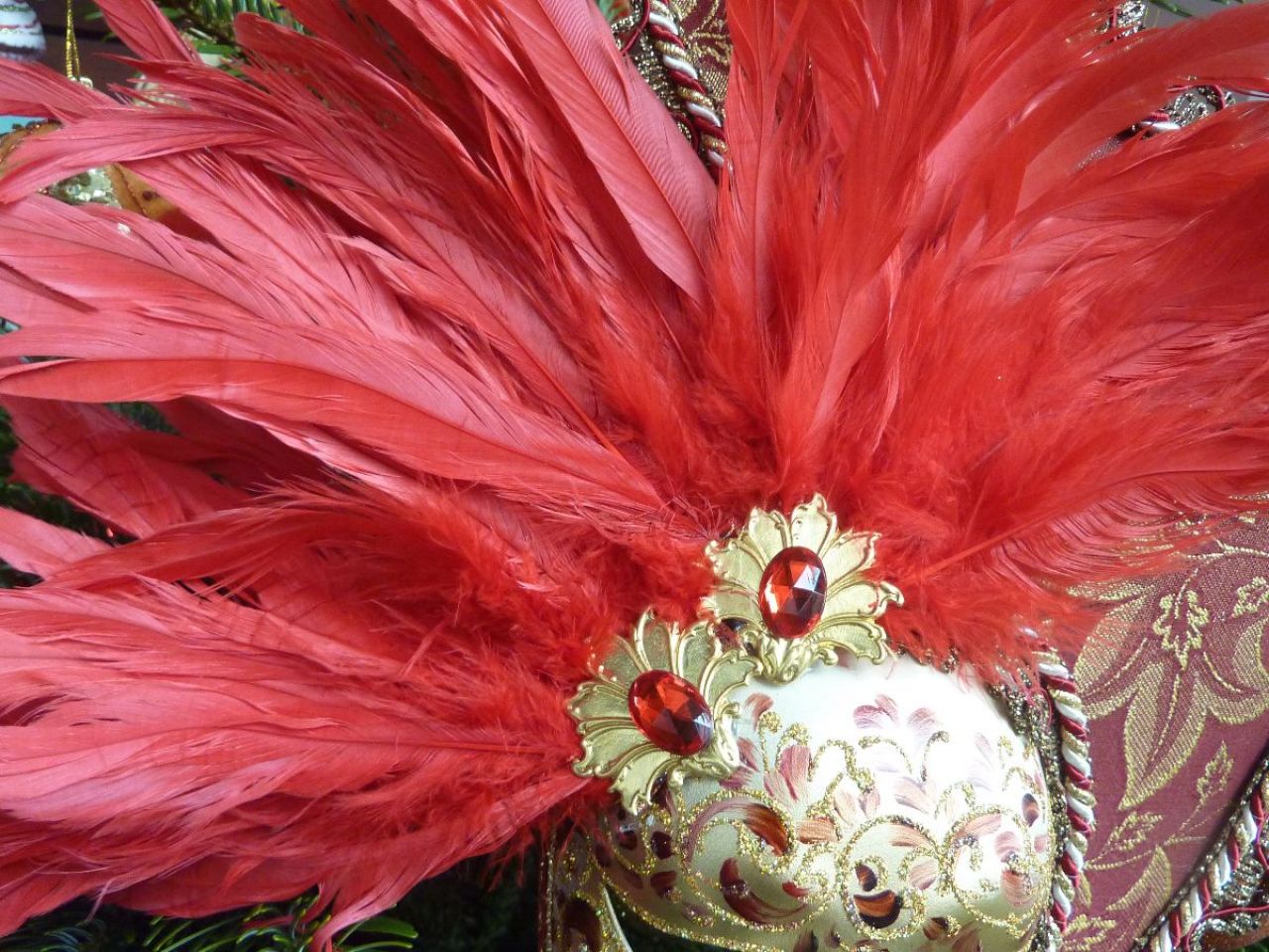 masque pour décoration avec un petit visage entouré par des plumes et du tissu, sur le front 2 bijoux