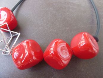 collier avec grandes perles rouges soufflées, élément geometric en acier , fil en gros caoutchouc